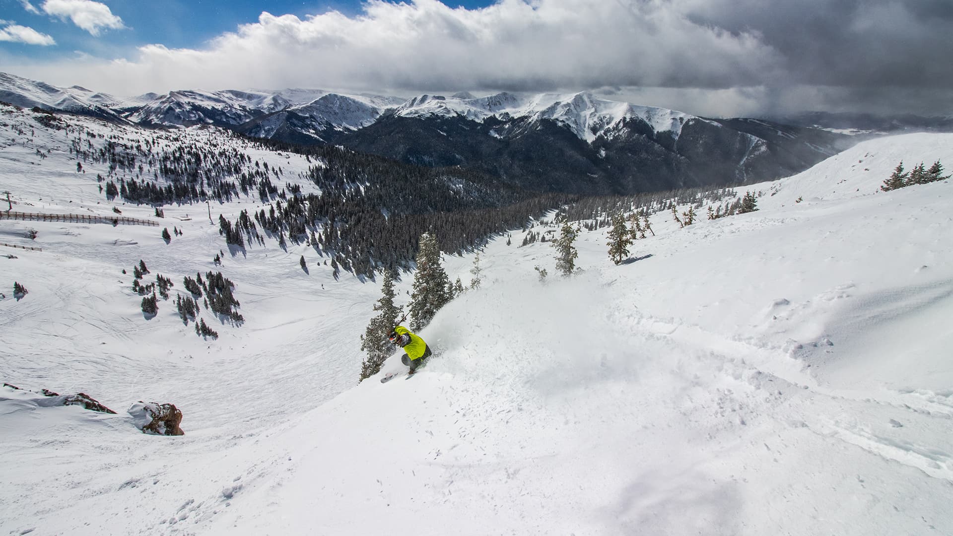 Skier descending a mountain covered in powdery snow.