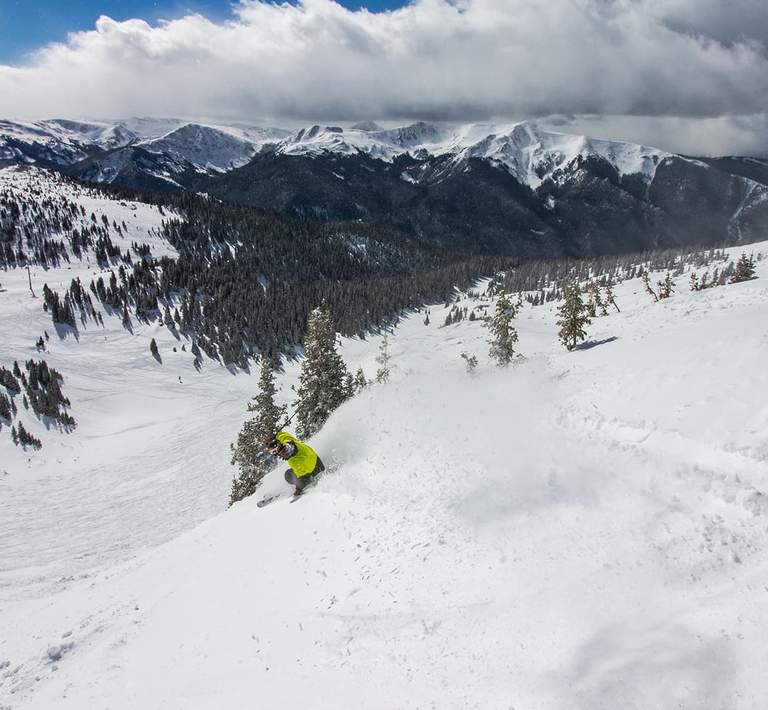 Skier descending a mountain covered in powdery snow.