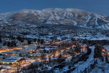 Aerial image of a snow-covered town at the base of a mountain.