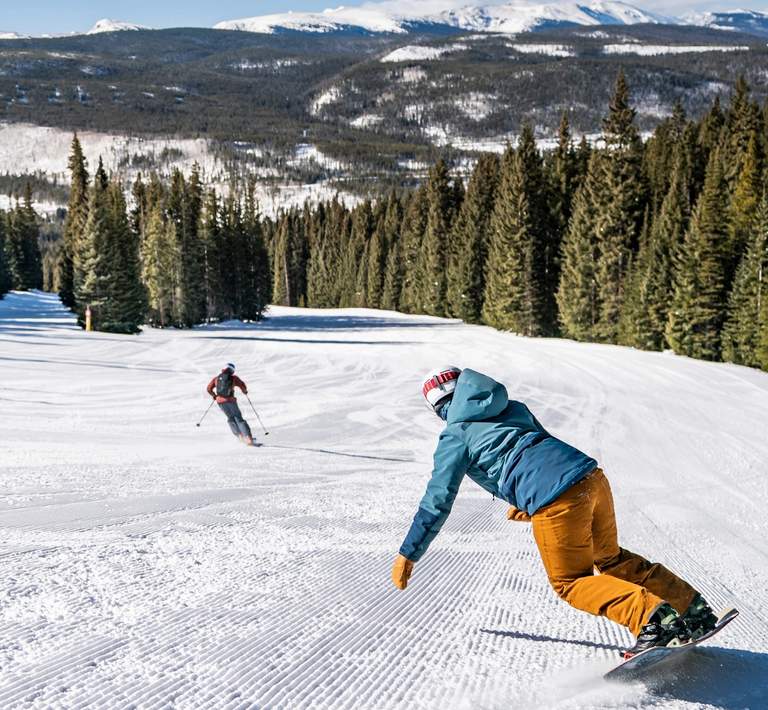 group of people skiing and snowboarding on a groomed run