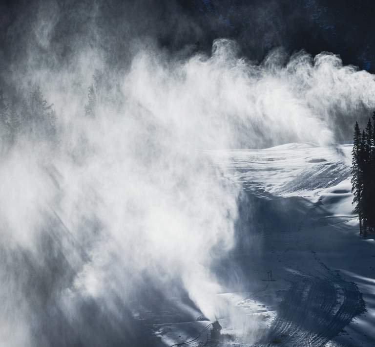 Snow guns blasting snow on a ski hill