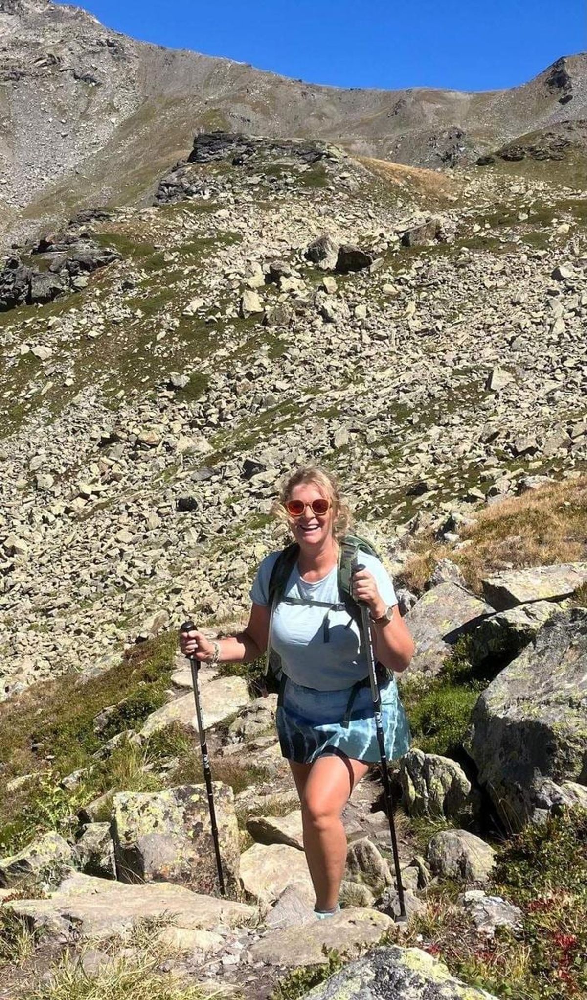 A walker with poles climbing a rocky mountain path