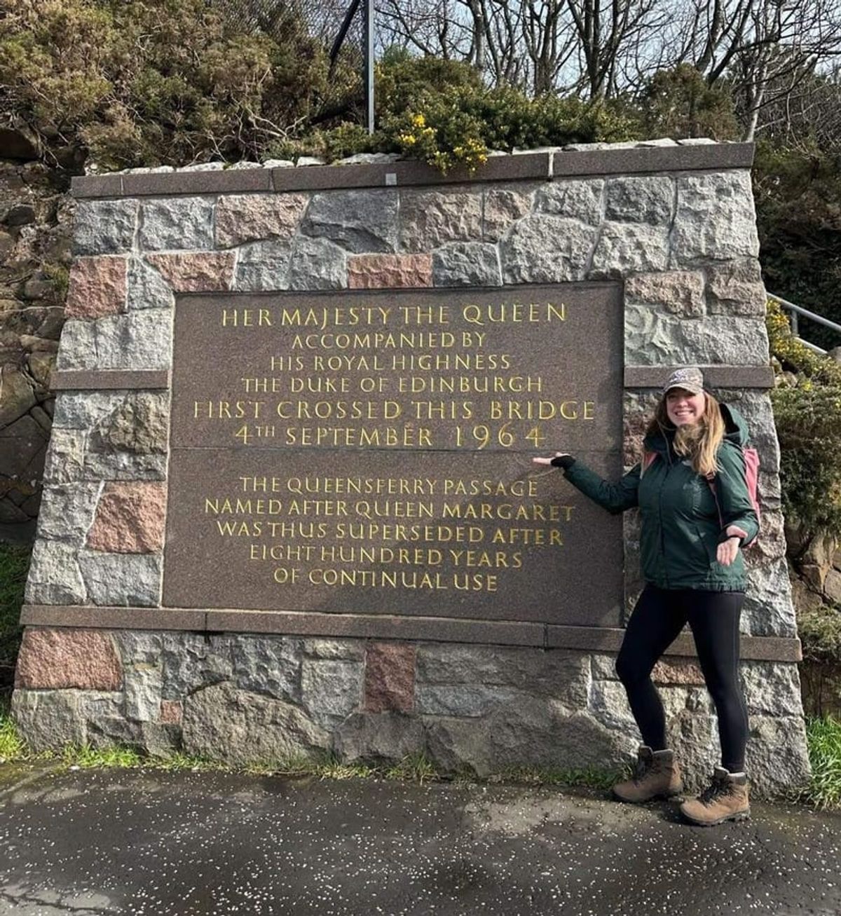 A stone monument to the Queensferry Passage with a walker beside it
