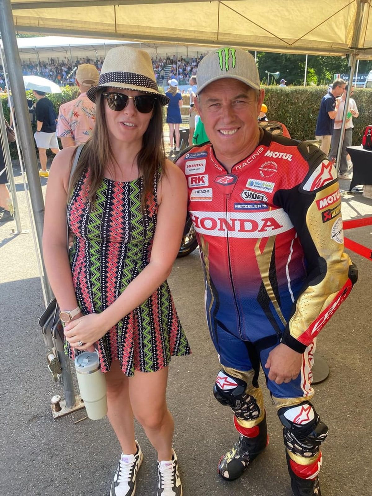 A woman standing beside a racing driver in full leathers at a track event