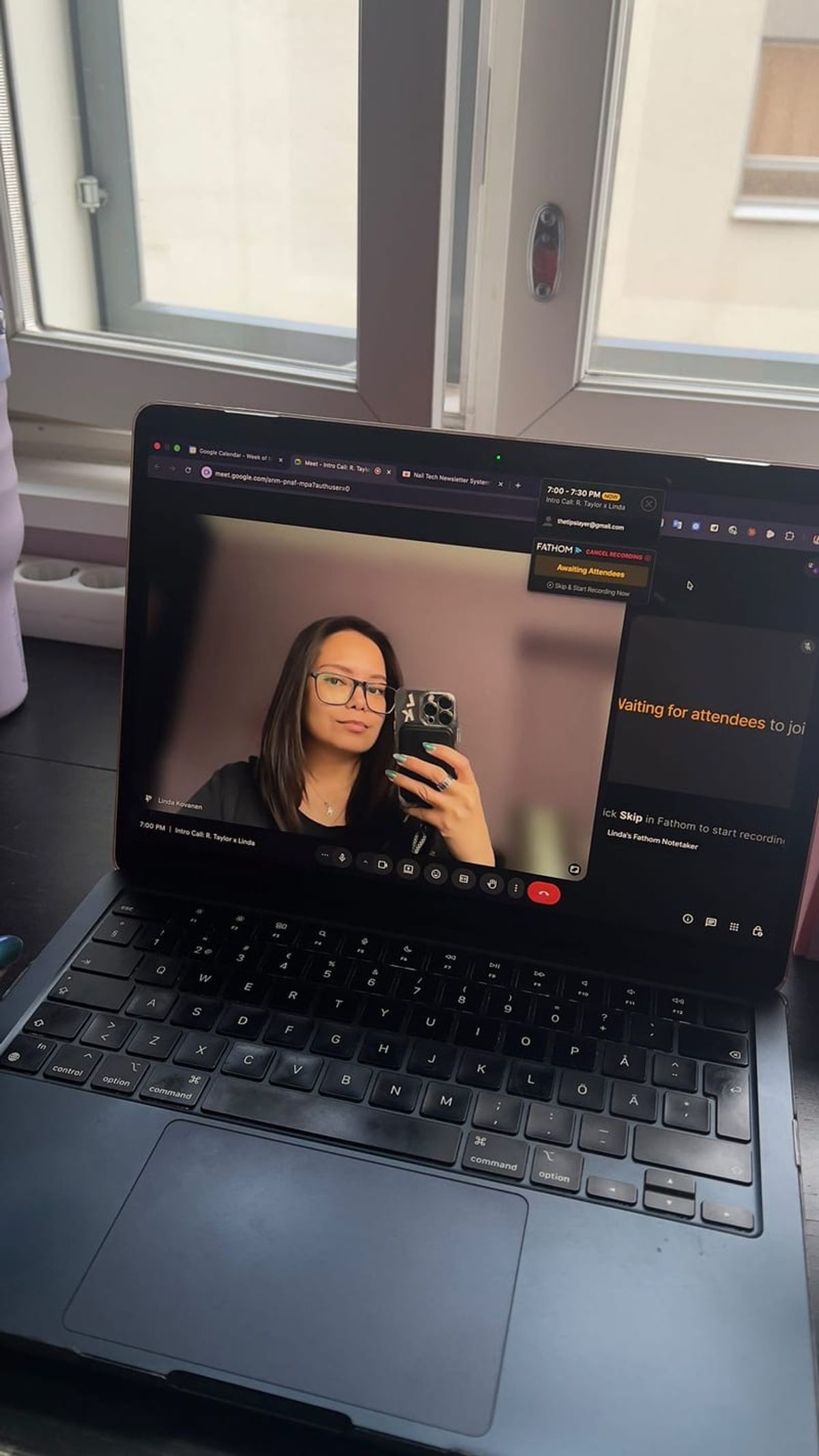 A laptop open on a call, Linda reflected in the screen