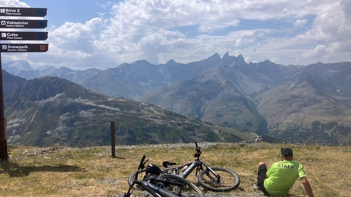 Two mountain bikes laid down on a high alpine track above a valley