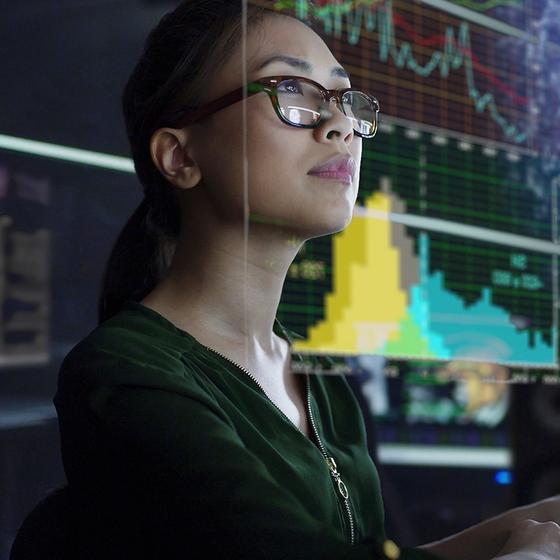 Woman working on a computer looking at financial charts
