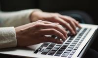 Woman's hands typing on the keyboard of a laptop