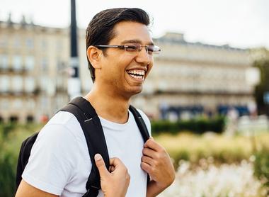 Male student with backpack standing and smiling