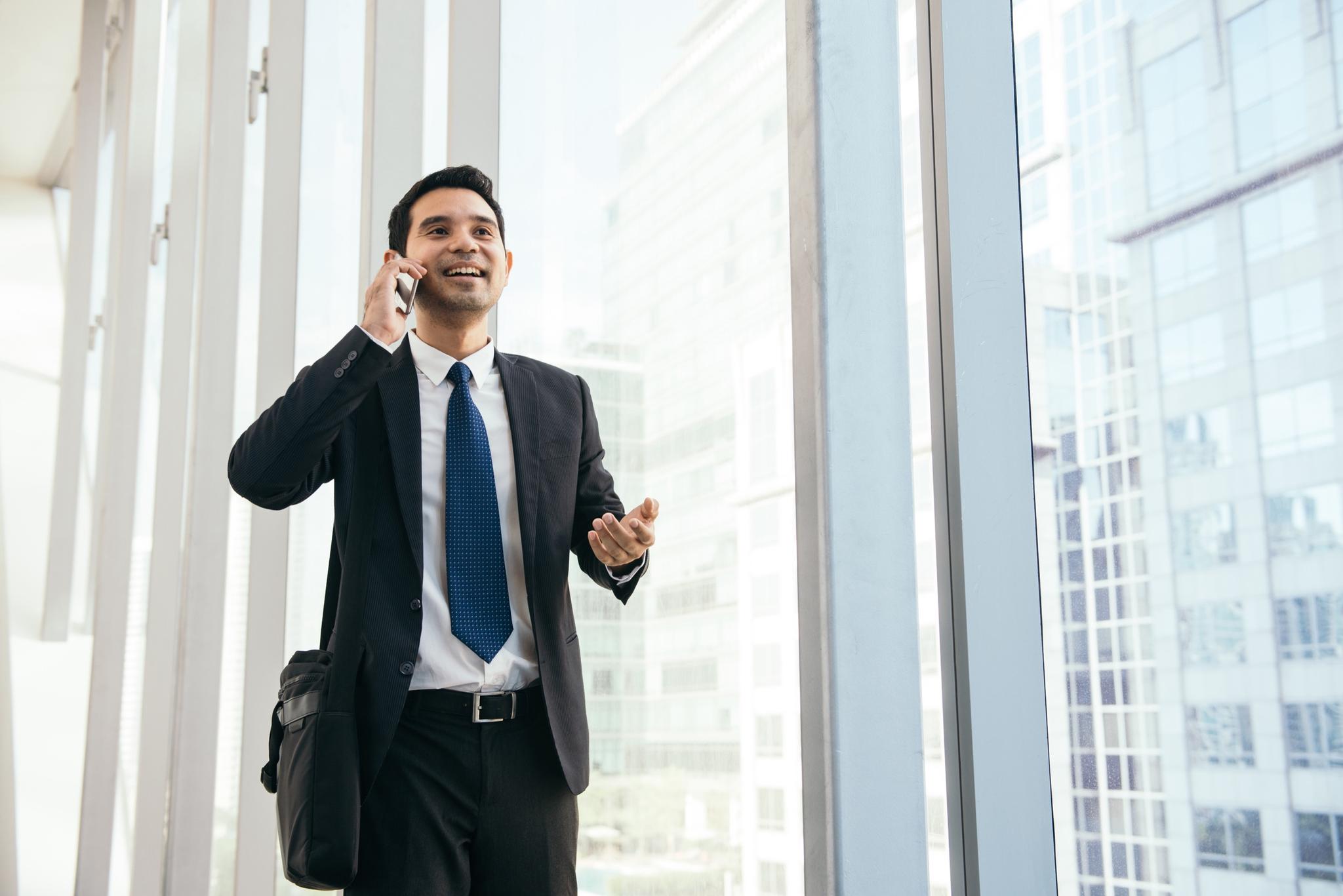 Business travellers A business traveller on a call by the windows of a city office tower