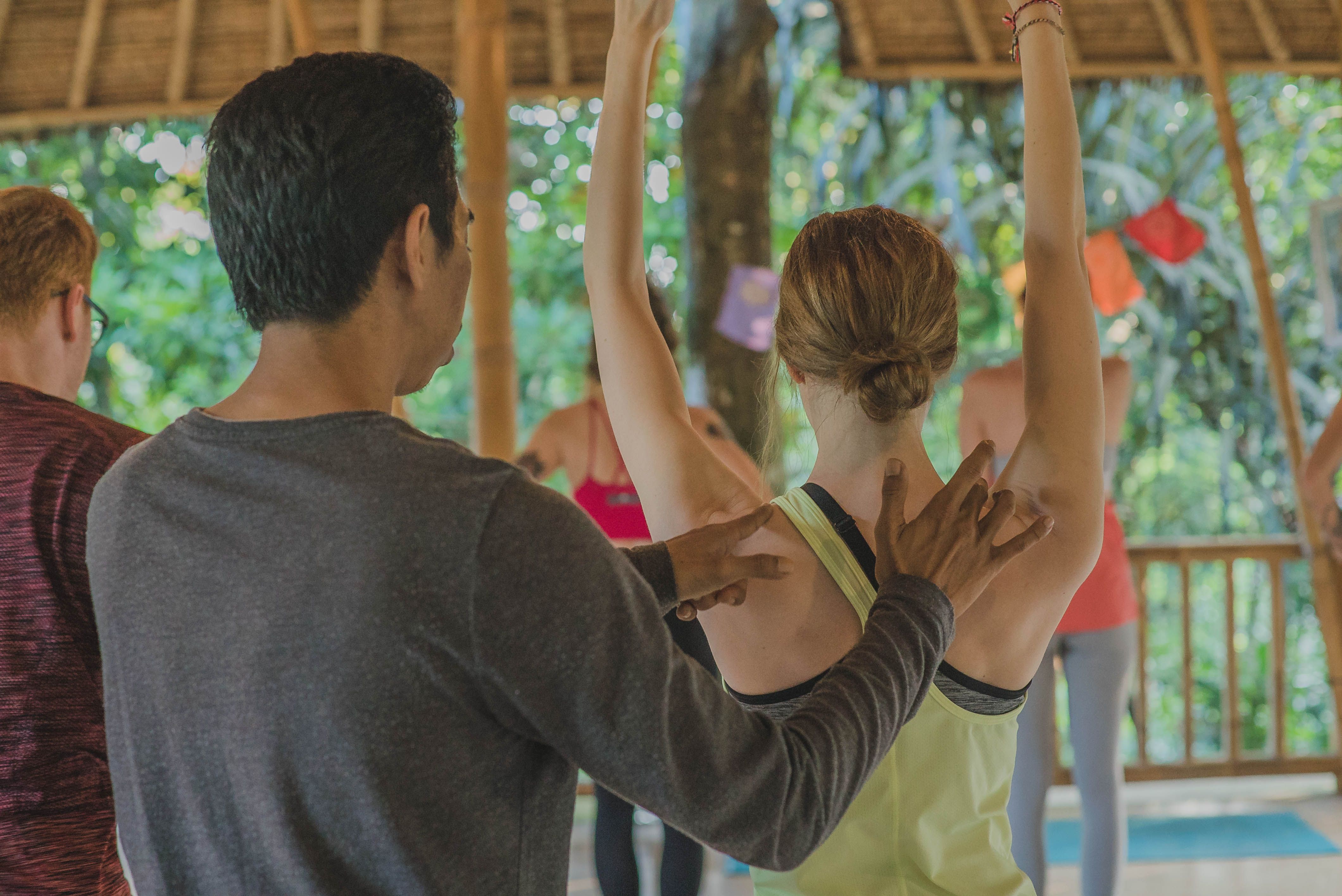 Ary/Yoga teacher adjusting the pose of a student
