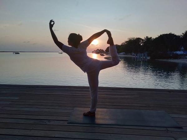 Ita in a yoga pose on a shore of a lake.