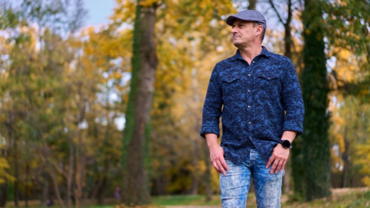 Persoon met pet wandelt door een park met herfstkleurige bomen