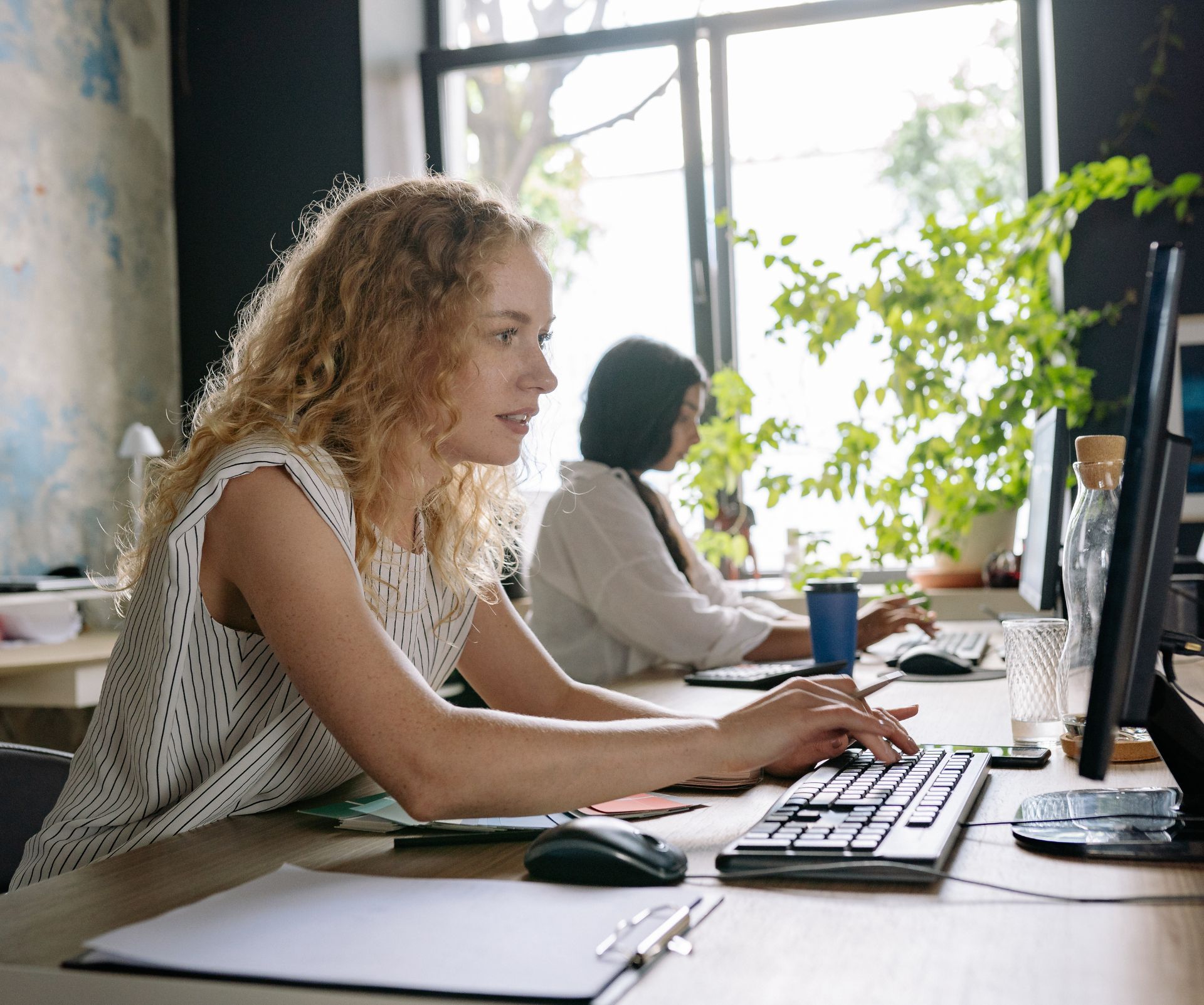 Medewerker werkt geconcentreerd achter een computer in een licht kantoor.