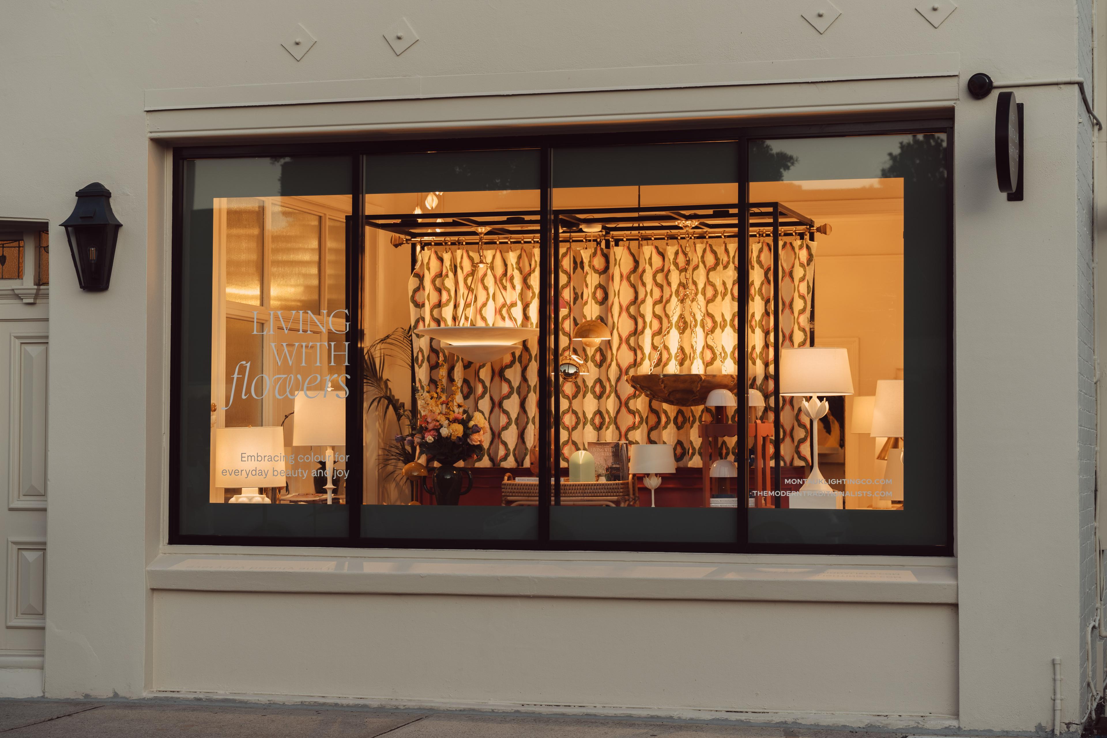 The Townhouse shopfront at dusk, its window lit by lamps and patterned curtains
