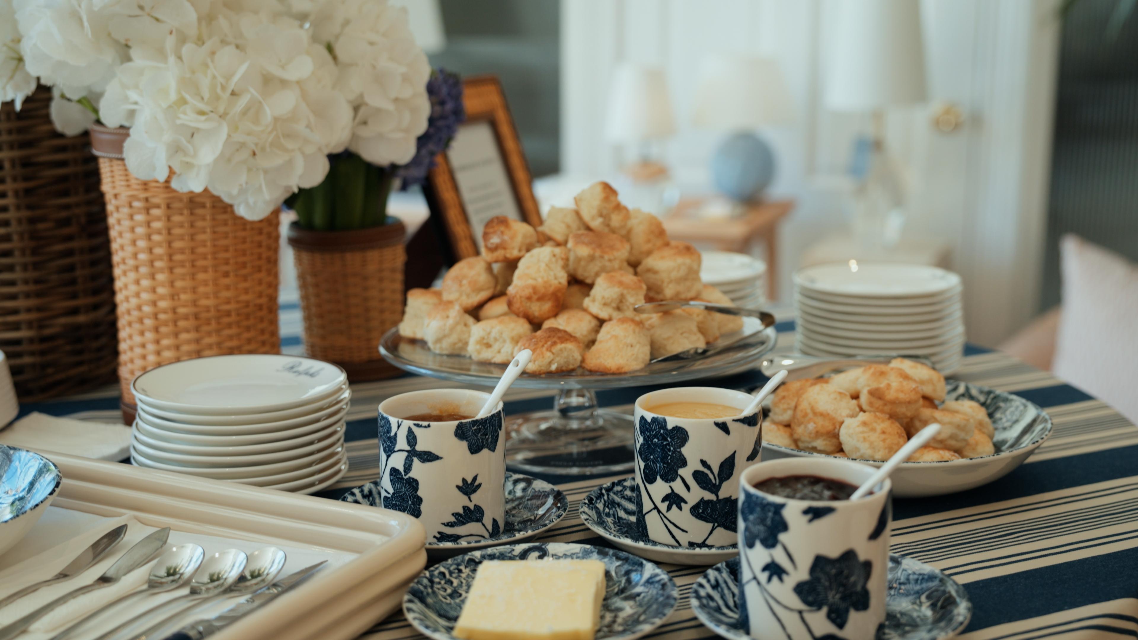 Scones and blue and white teacups set out on a striped tablecloth