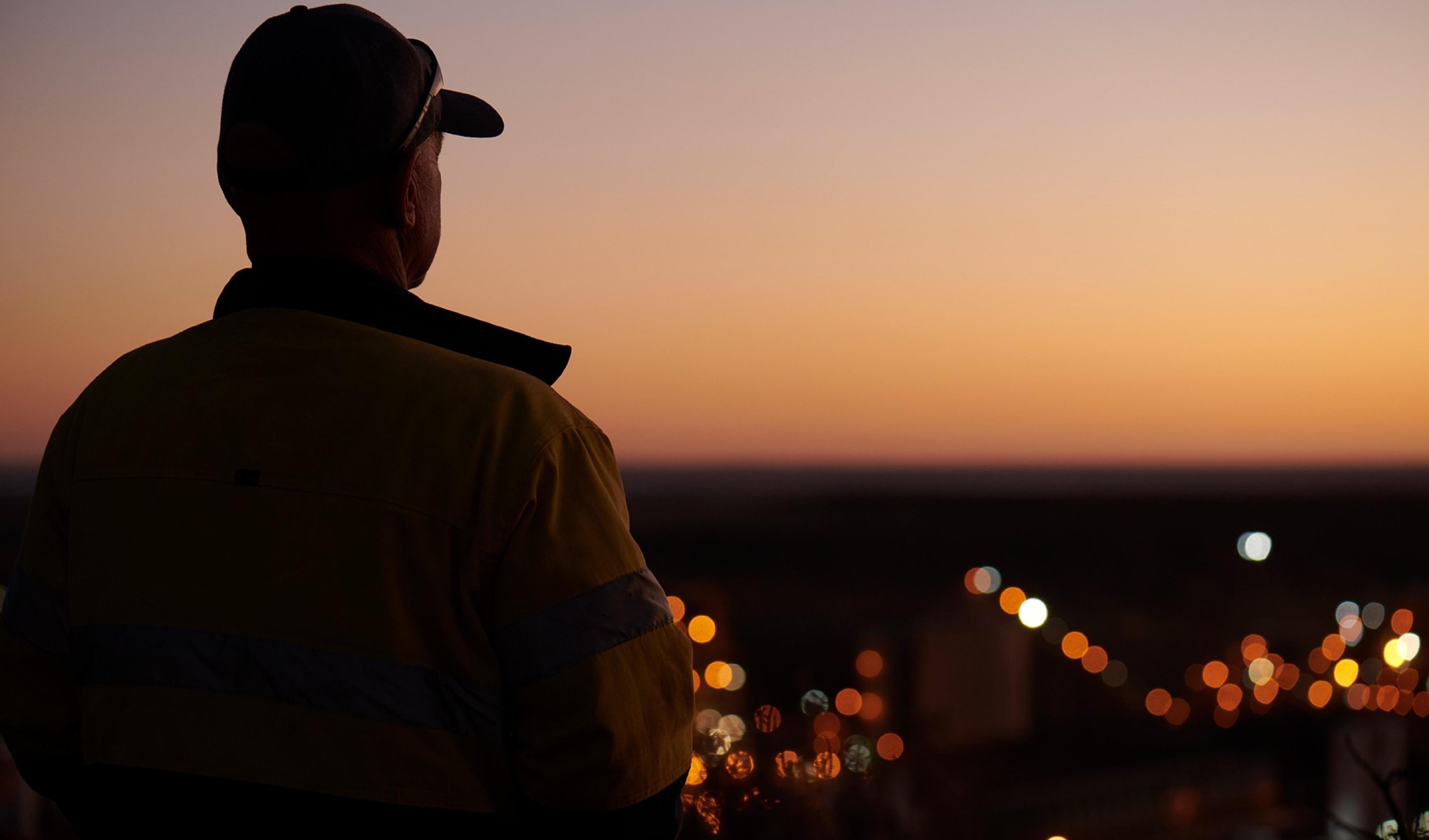 Worker looking out over site lights at dusk