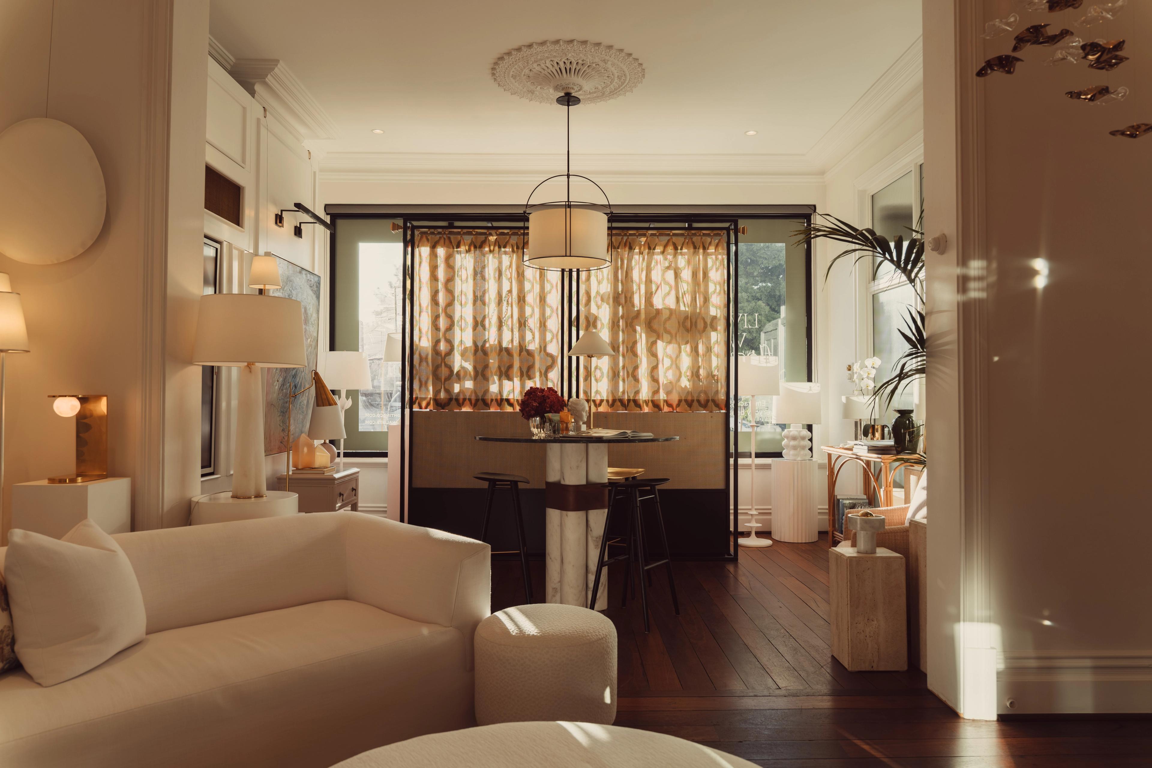 A sitting room at The Townhouse in late afternoon light, with a cream sofa and a pendant over the dining table