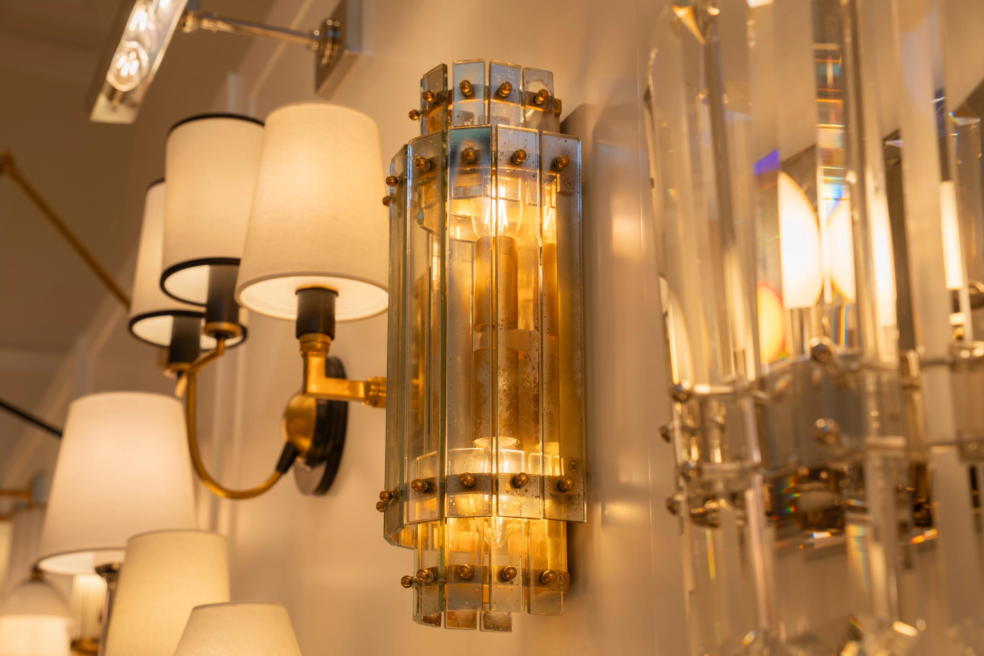 A glass and brass wall sconce among shaded wall lights