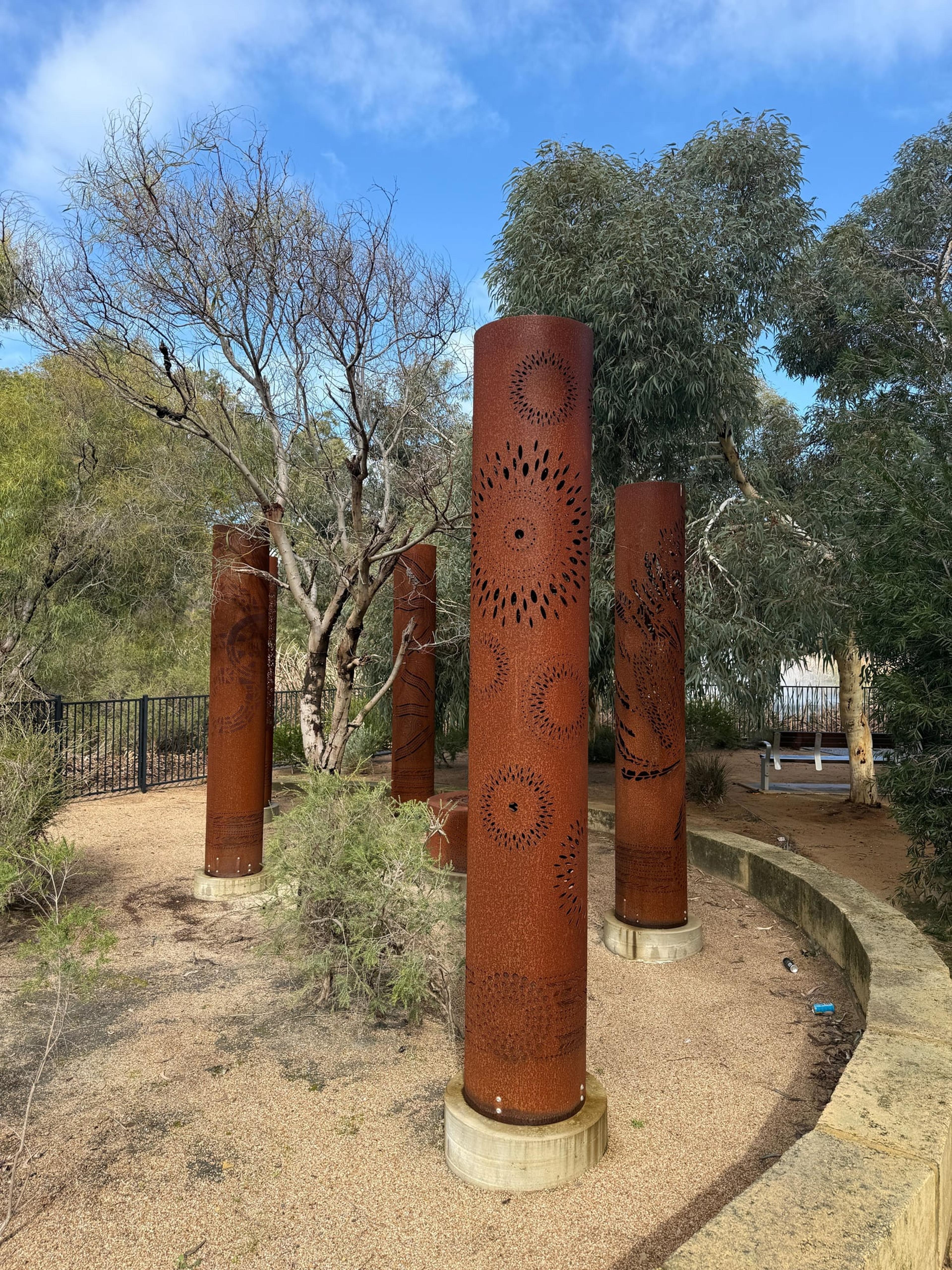 Three rusted totems with the trees grown in around them