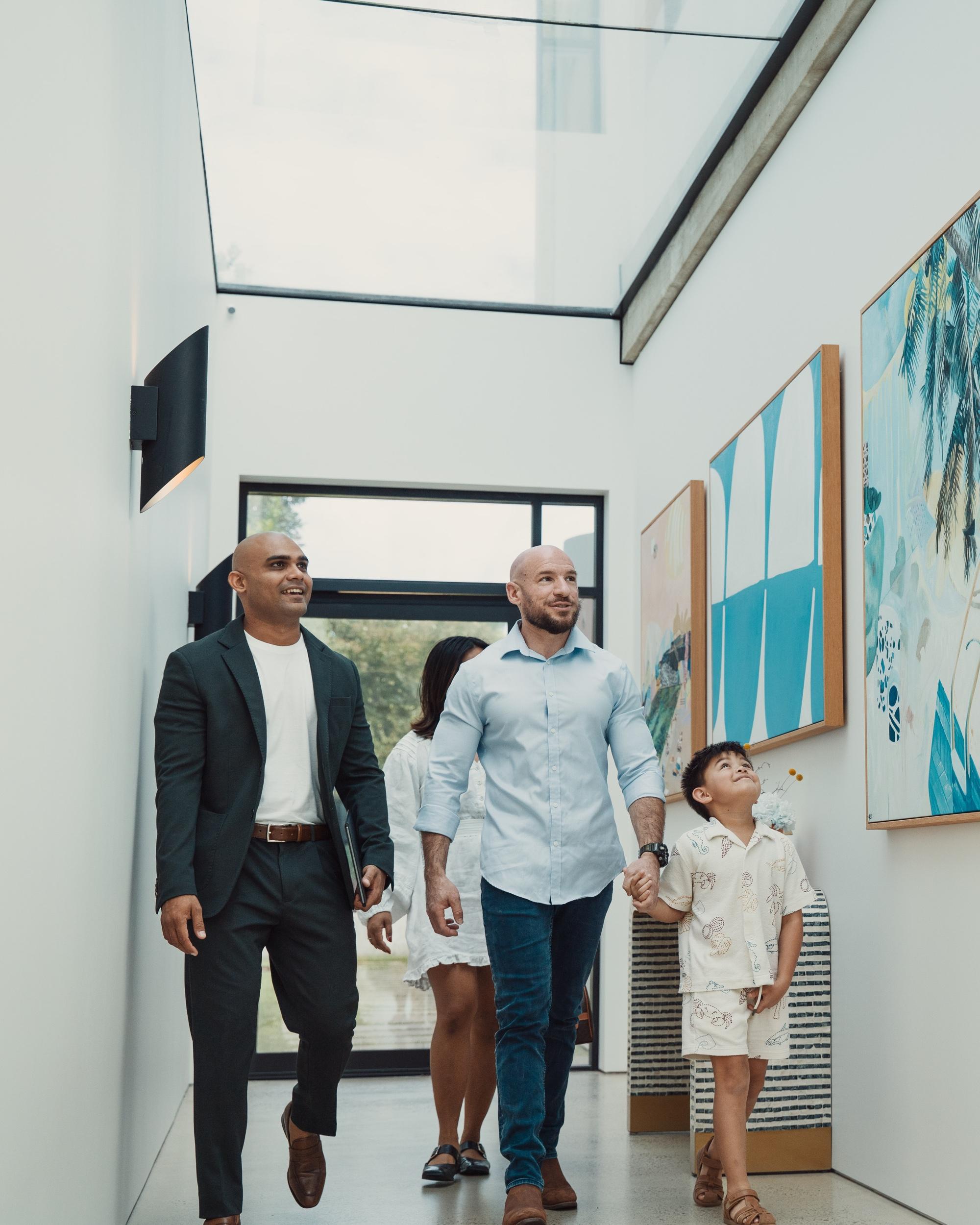 Find & Sign’s Niki walking a family through the gallery hallway of a home