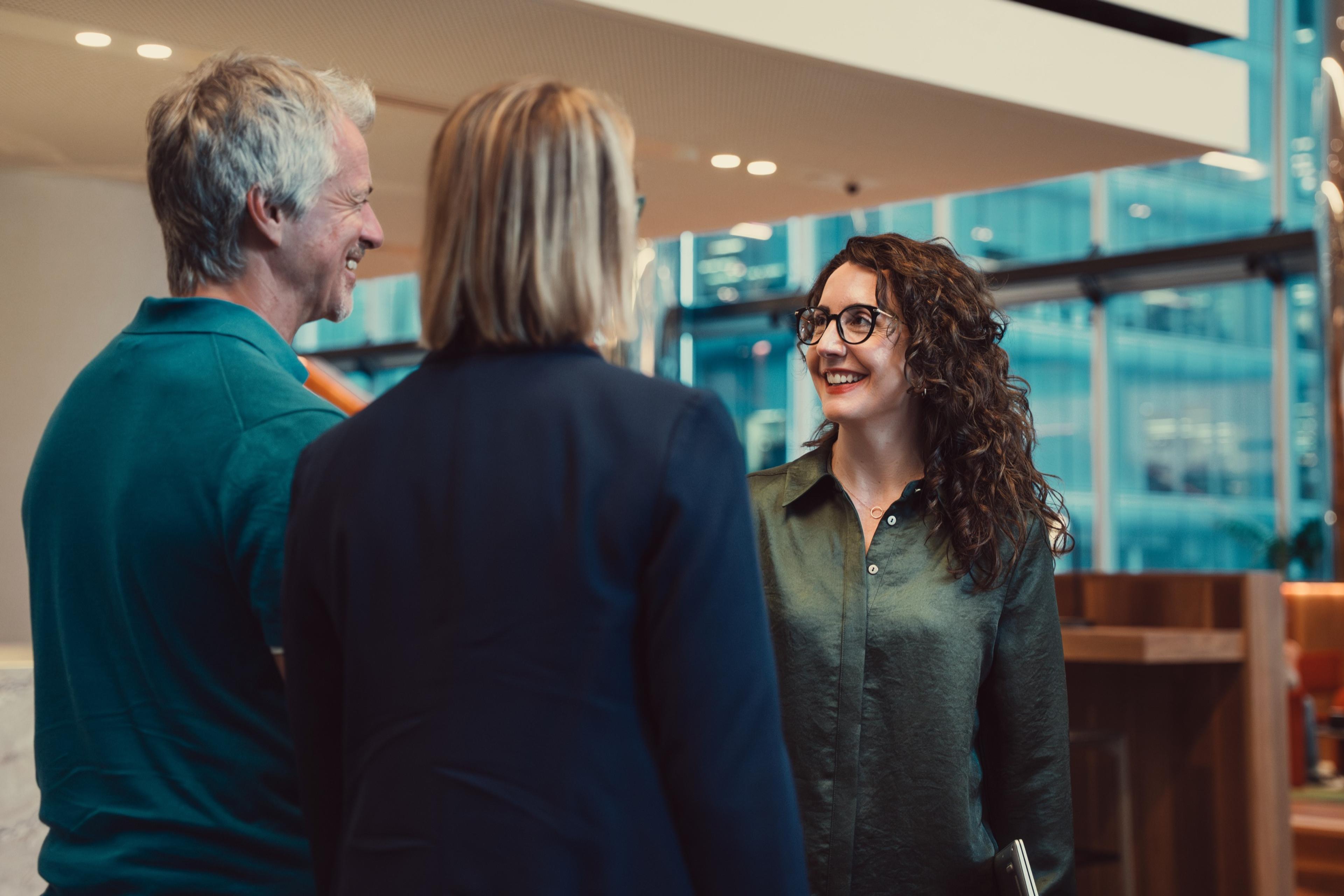 Two AKT Advisory partners talking with a client in an office lounge
