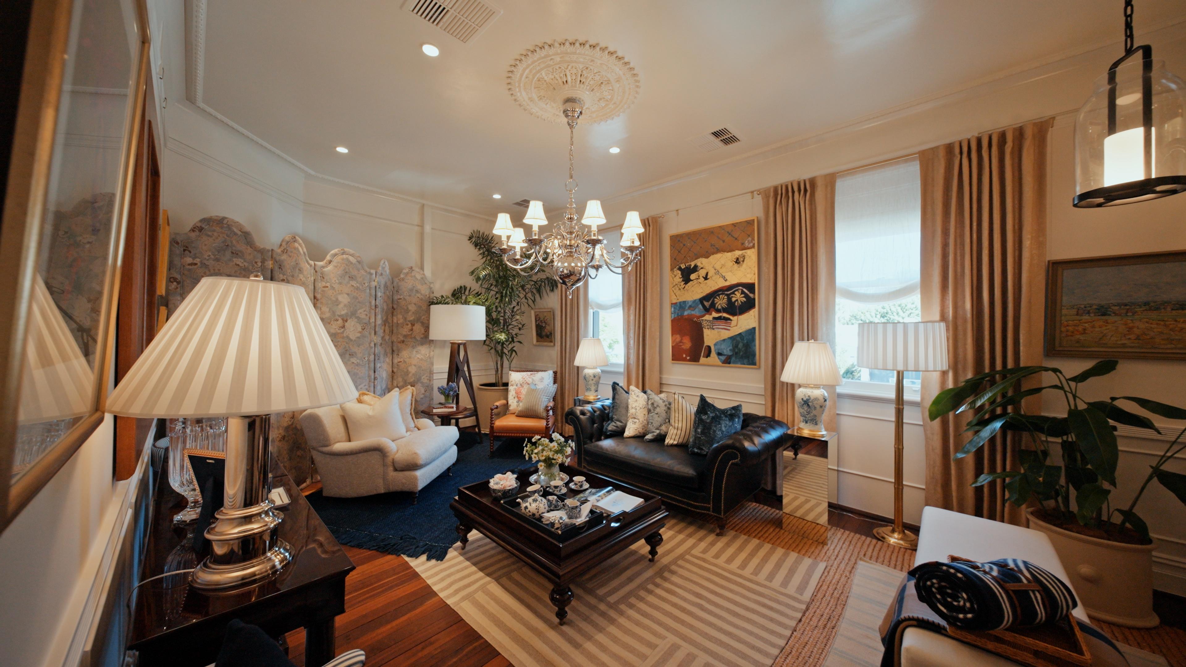 A living room in the gallery, with a chandelier, a leather sofa and pleated lamps