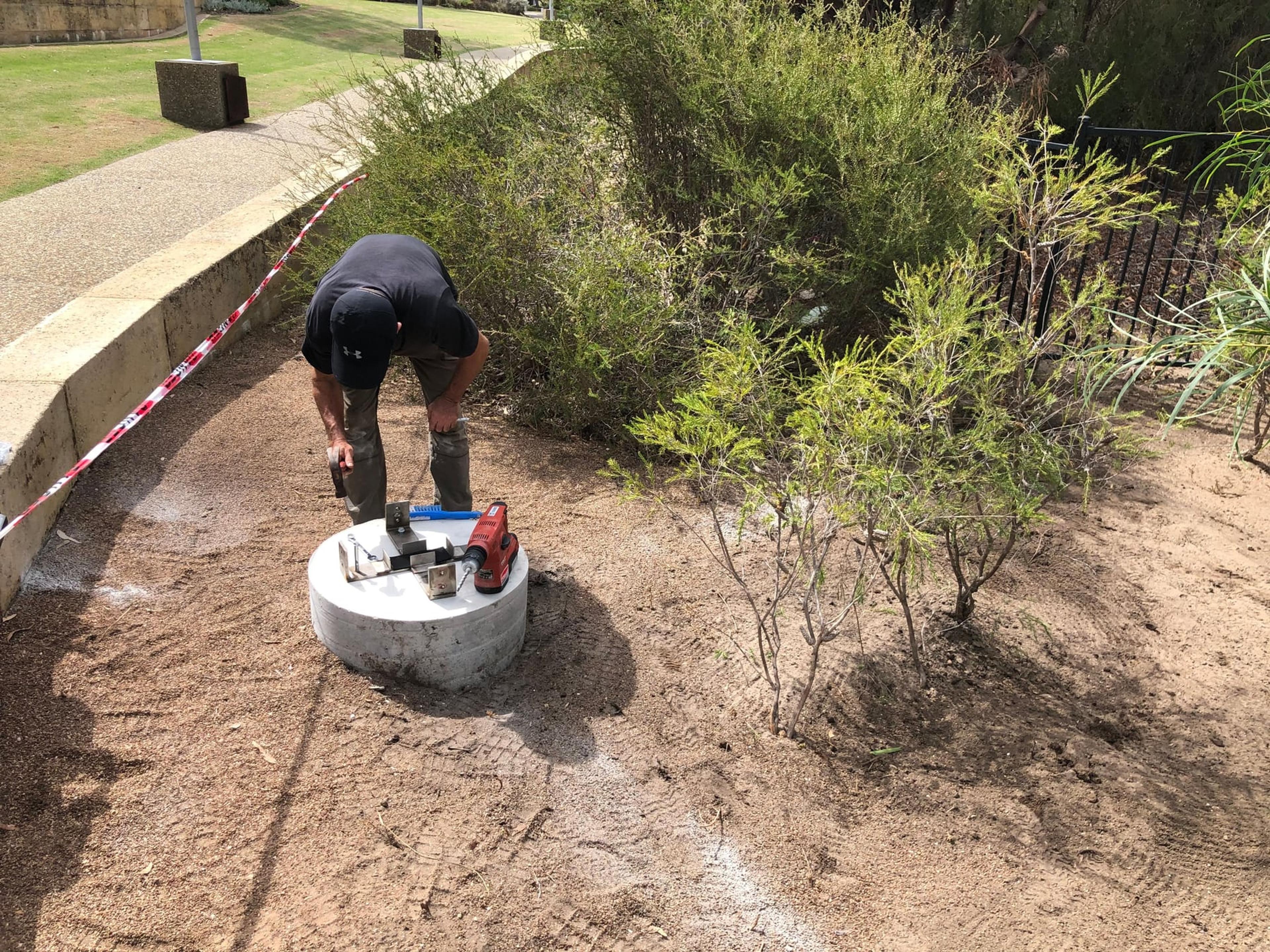 An installer fixing bolts into a concrete footing