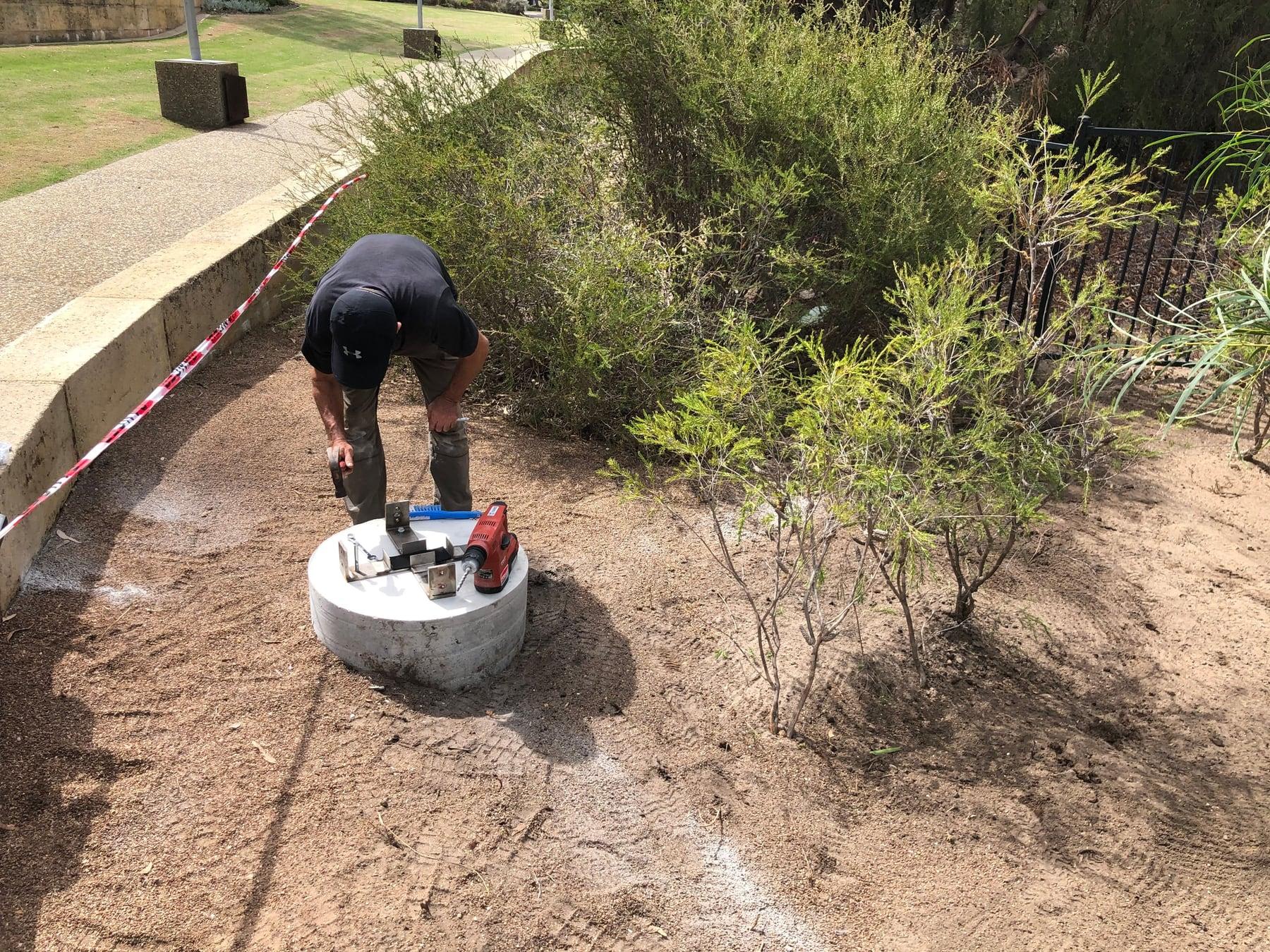 An installer fixing bolts into a concrete footing