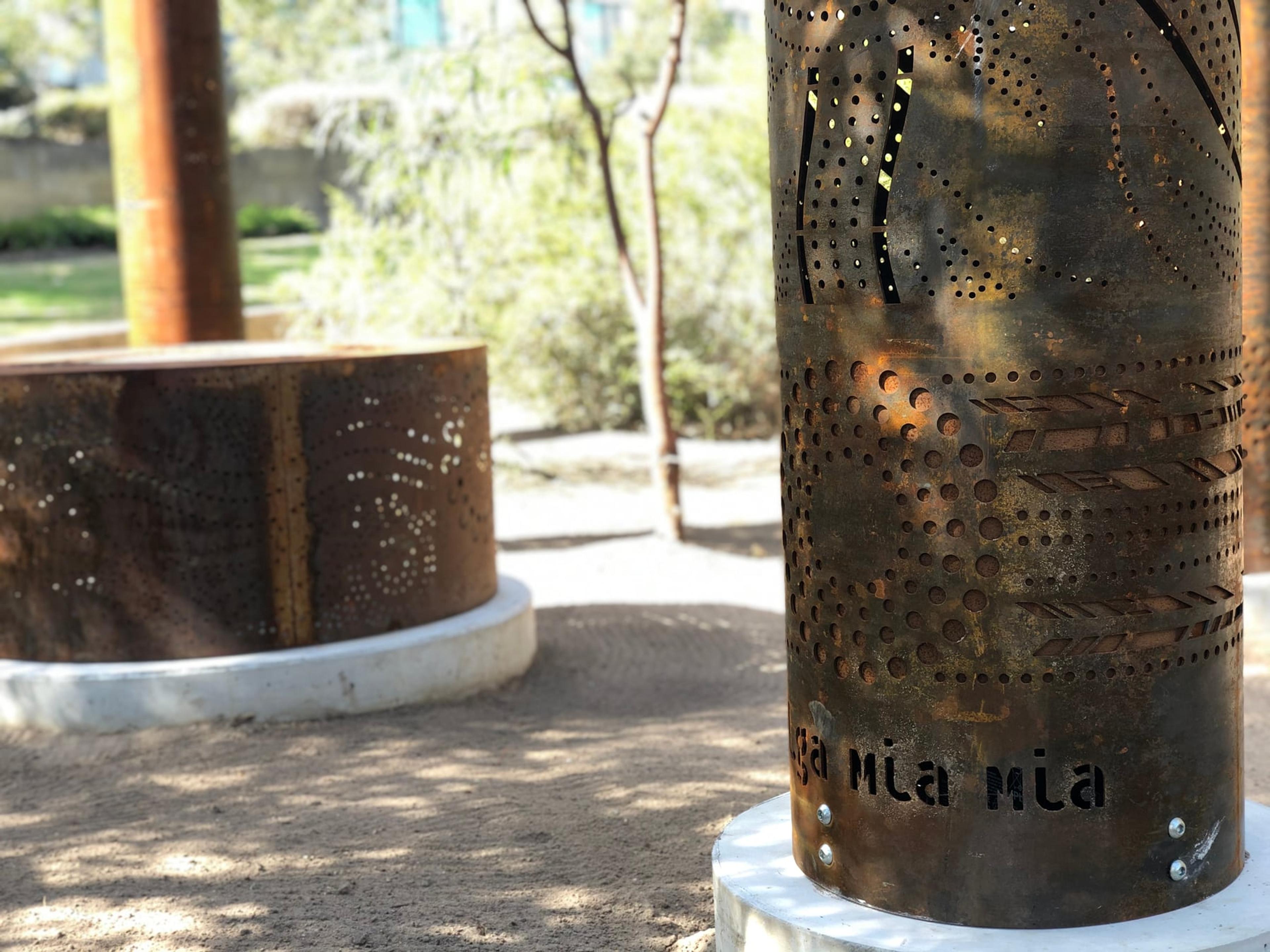 A close view of a totem and the fire pit in dappled sun
