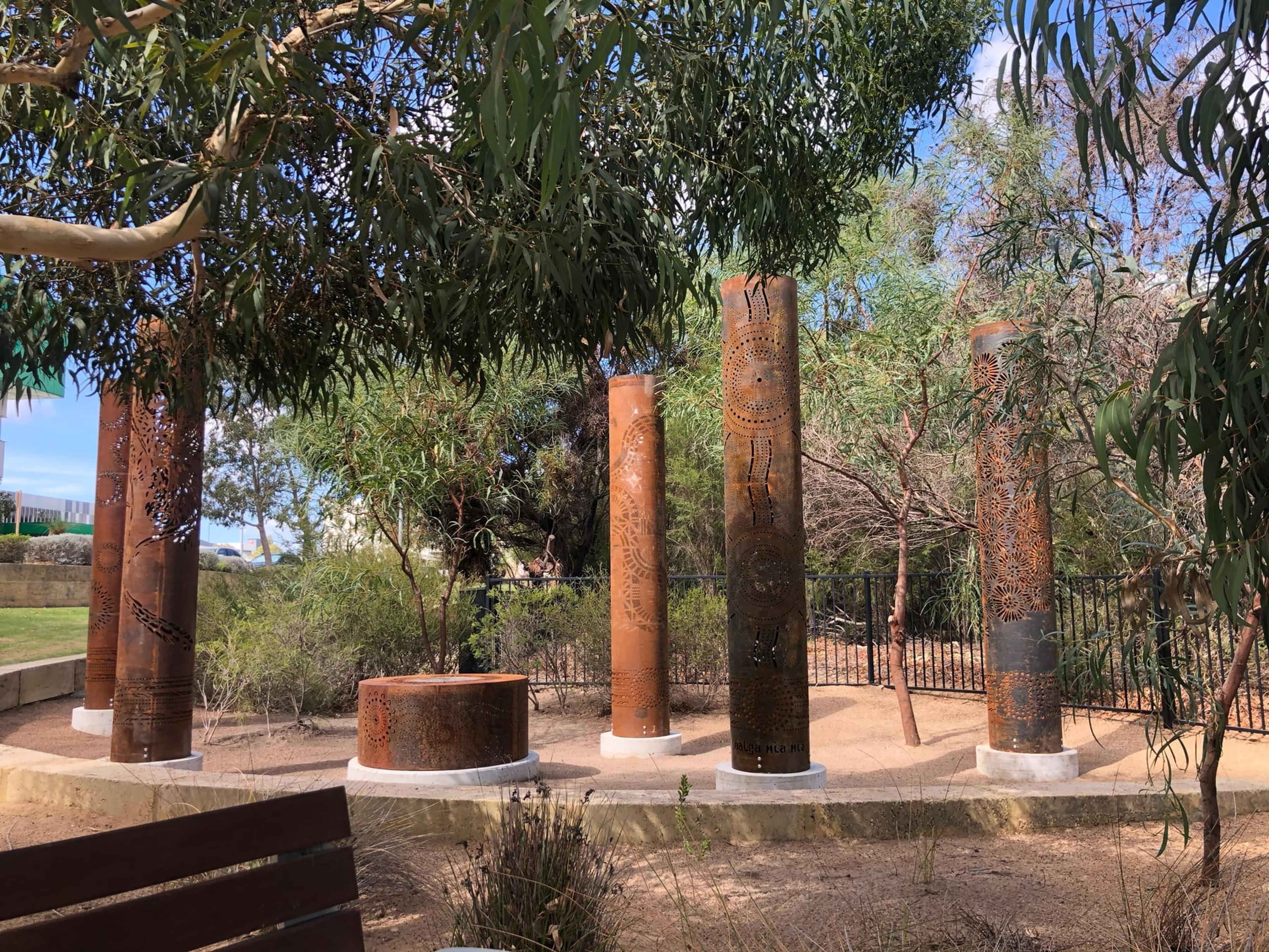 Five totems and the fire pit under gum trees by day