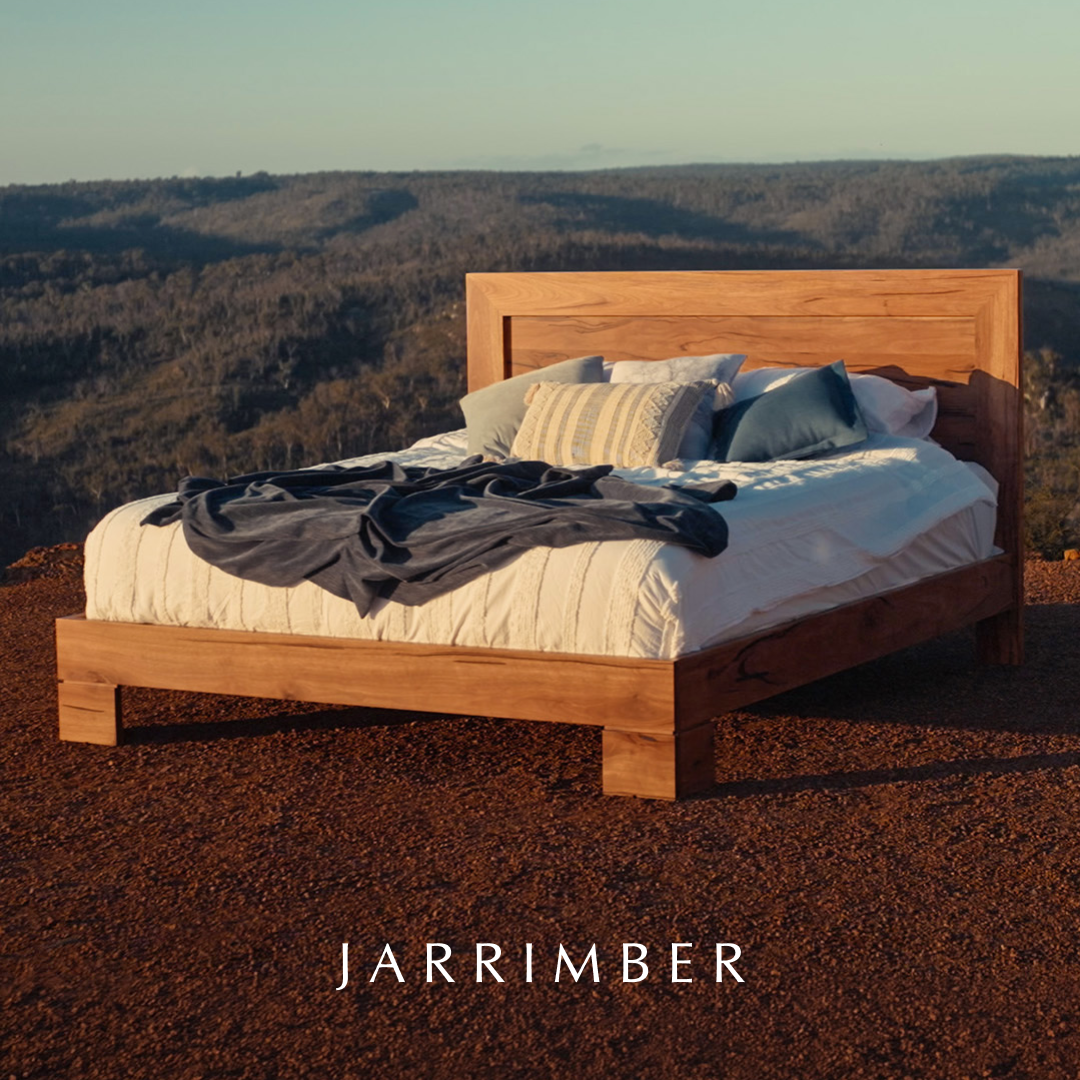 Ad showing a timber bed made up on red earth above a WA valley at dusk