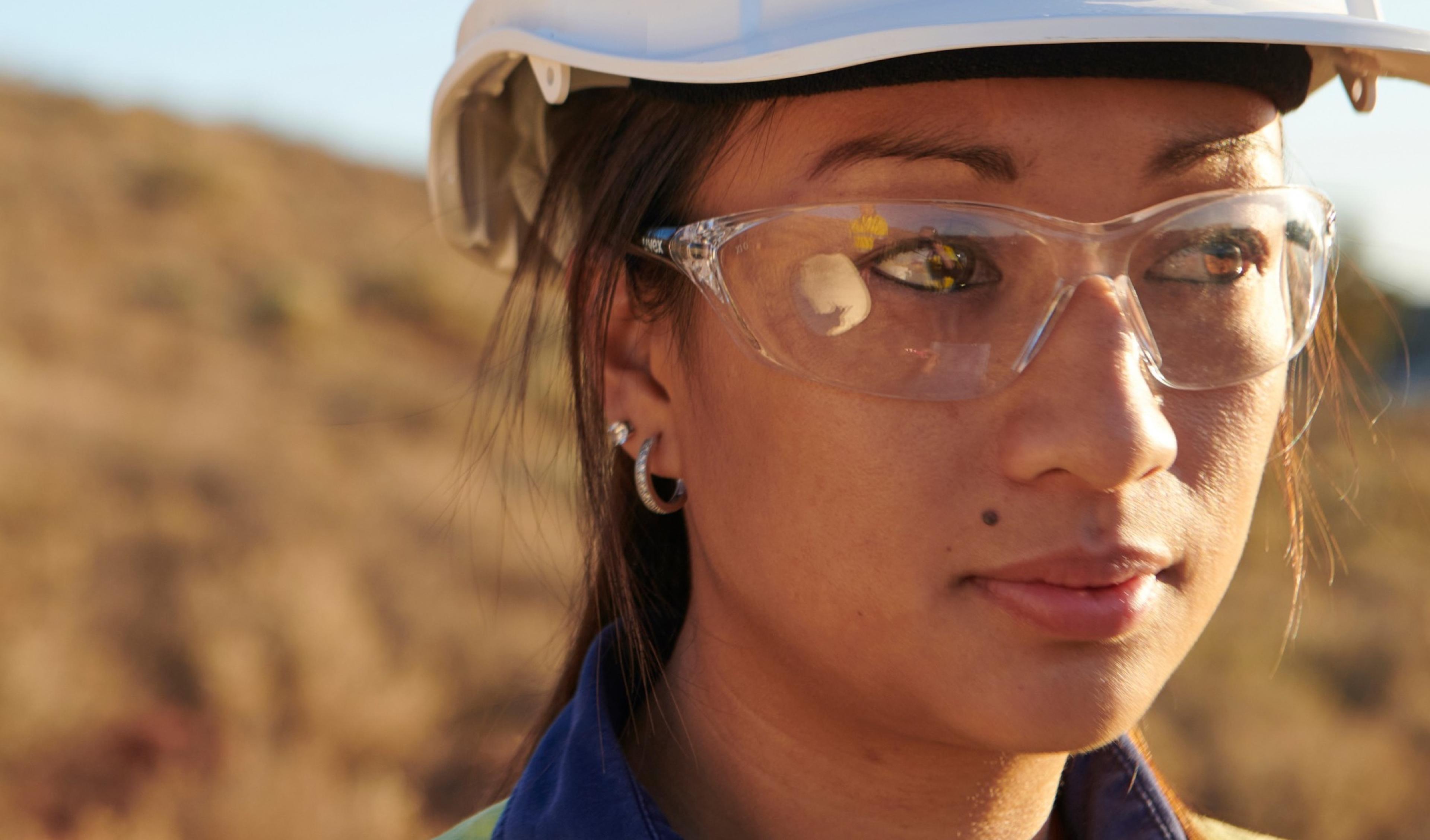 Close portrait of a worker in a hard hat and safety glasses