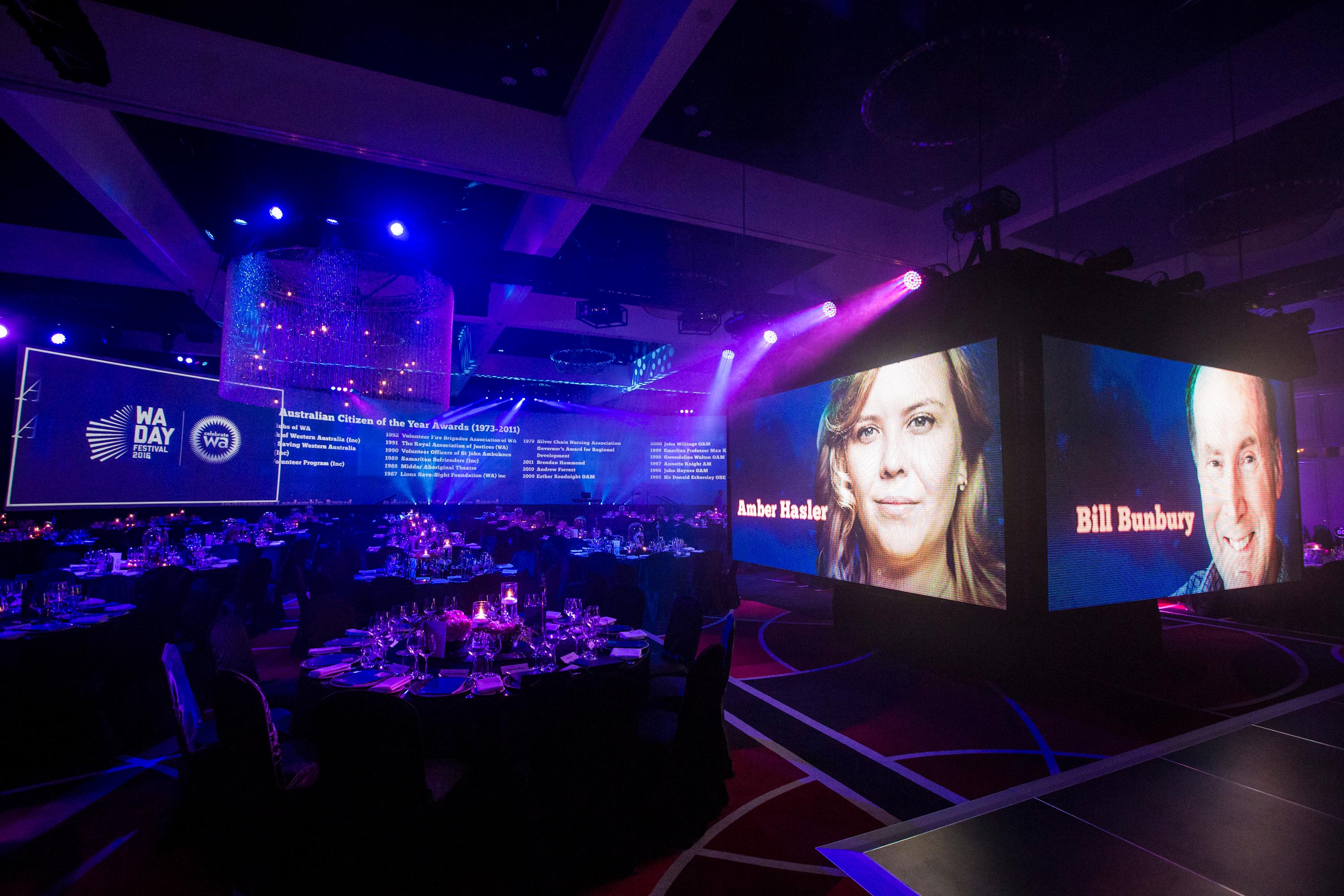 Honourees shown on the big screens above the tables at the awards night