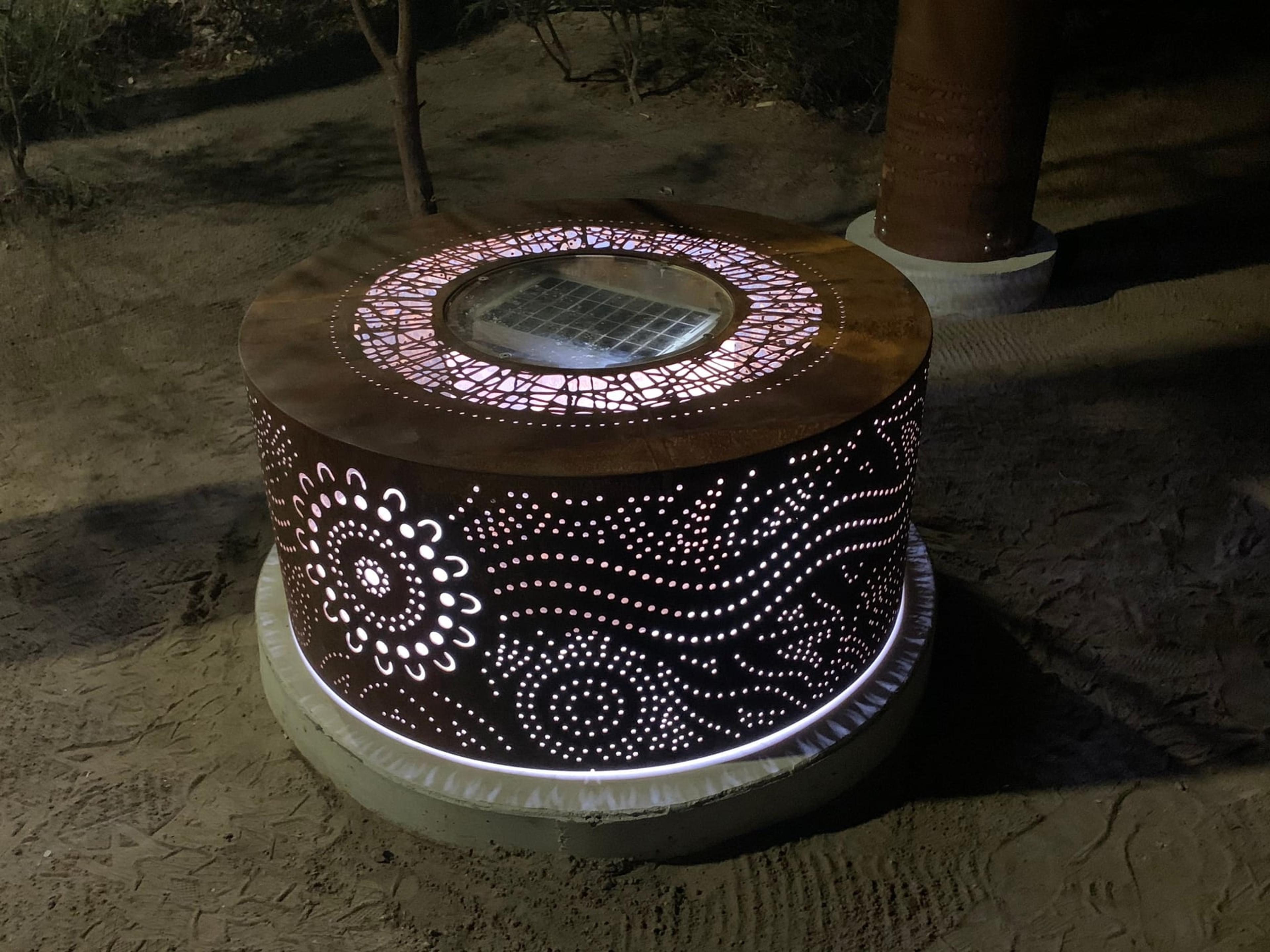 The fire pit at night, with dotted patterns glowing through the steel