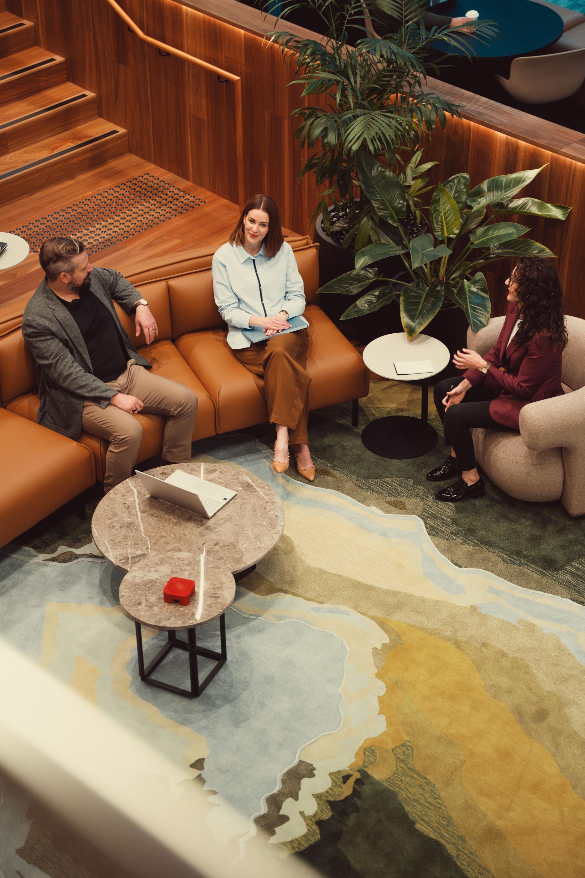 Three AKT Advisory partners talking on a lounge beside a patterned rug, seen from above