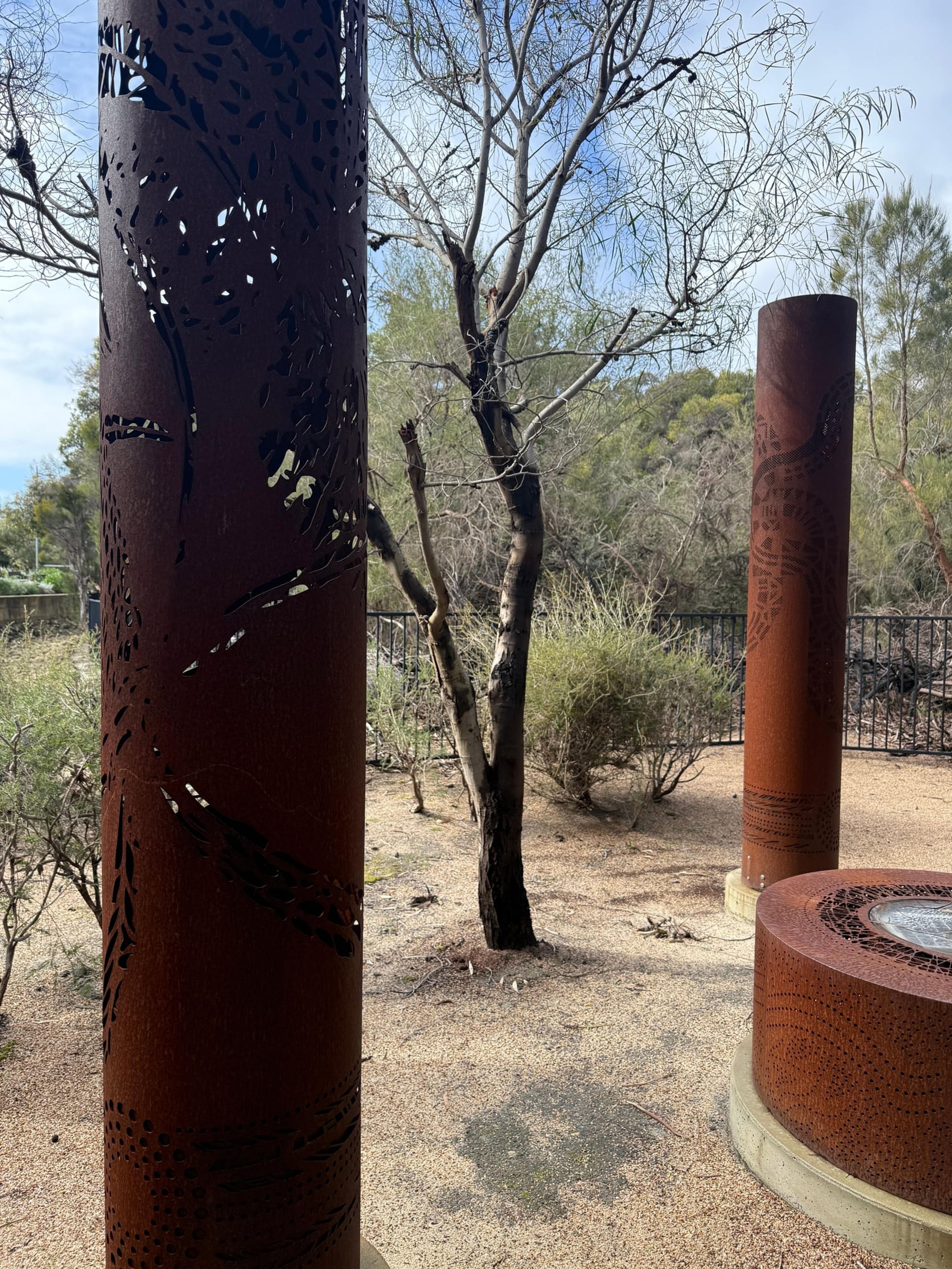 A dark weathered totem beside a bare tree