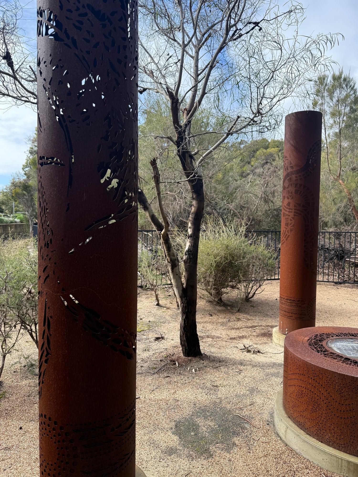 A dark weathered totem beside a bare tree