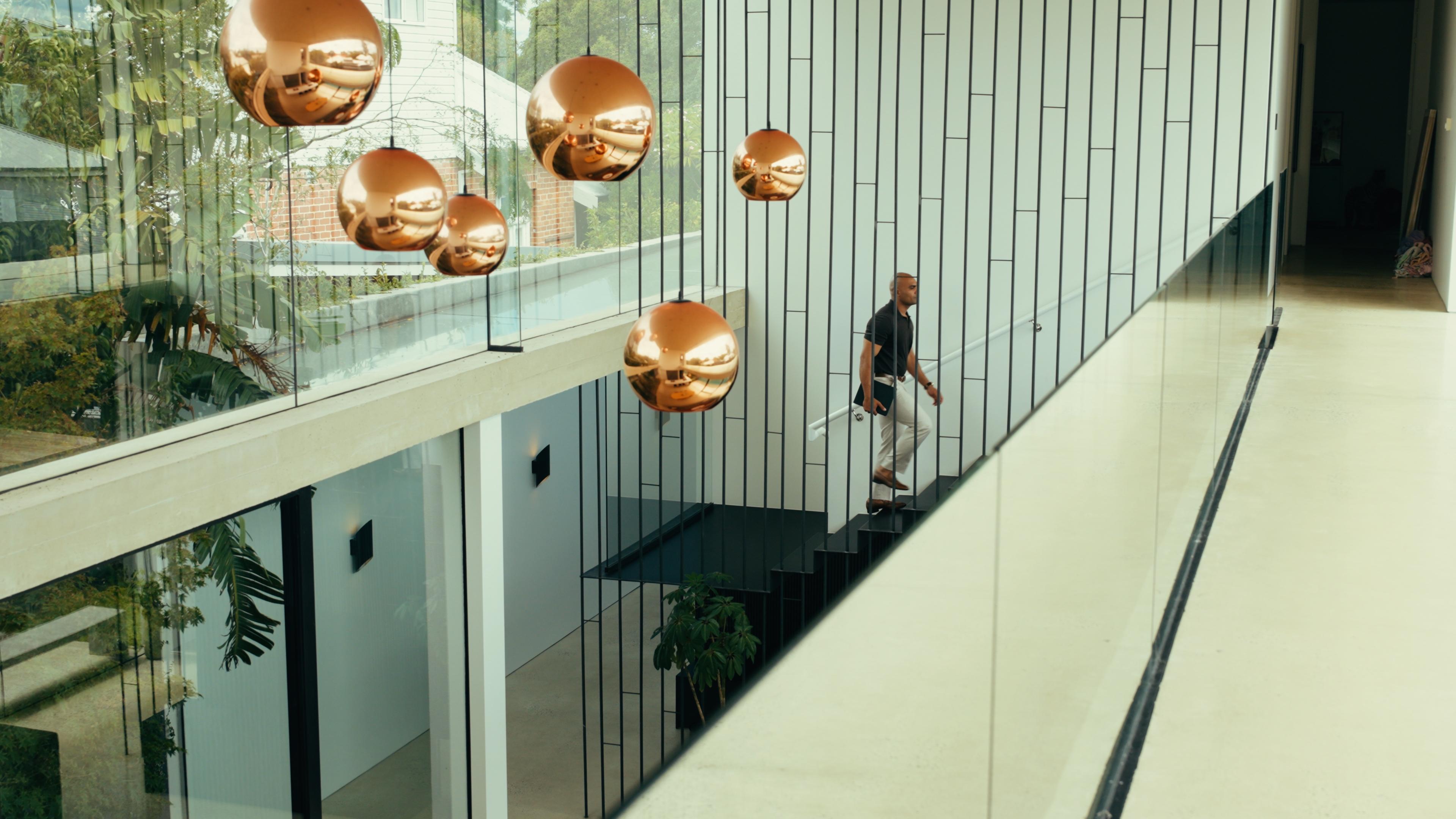 Walking up the staircase of a modern home under copper pendant lights