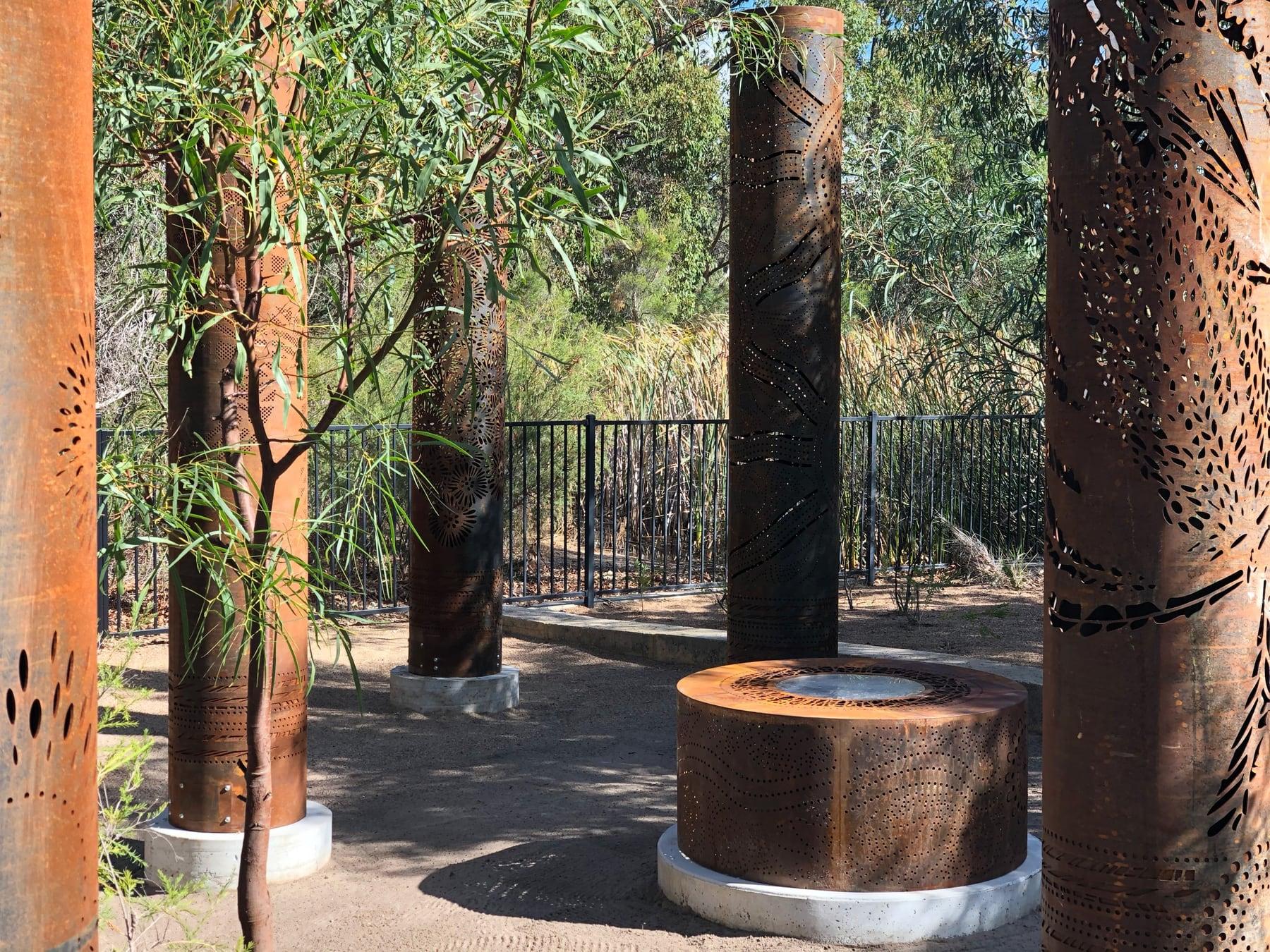Close view of a totem’s leaf pattern with the fire pit behind