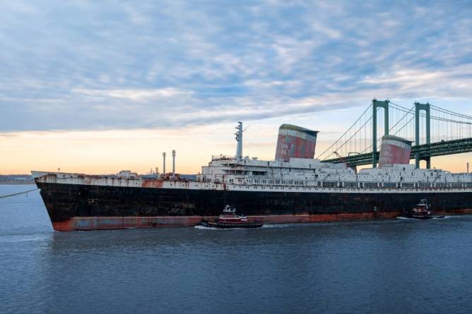 The SS United States being pulled by a tug boat