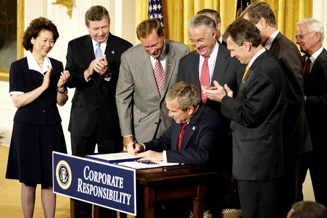 US President George W. Bush signs HR 3763 as members of the Congressional leadership and Cabinet members watch him sign the "Sarbanes-Oxley Act of 2002" in the East Room of the White House 30 July 2002. Credit: Stephen Jaffe/Getty Images