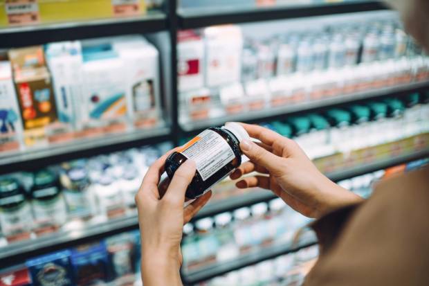 woman looking at supplement in store aisle