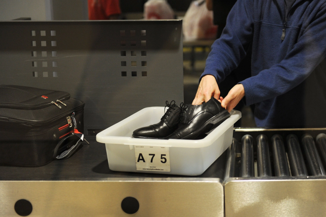 An air traveler places his shoes in a bin before passing through the TSA security check