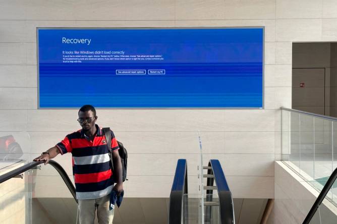 A blue screen of death (BSOD) showing on a monitor overlooking an escalator following the CrowdStrike incident in July.