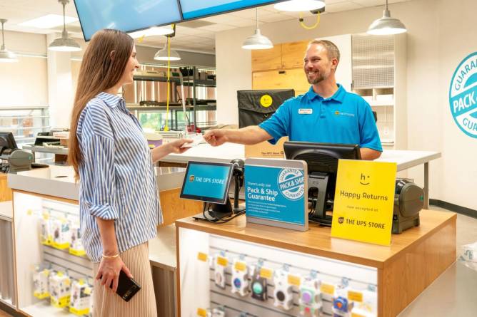 A Happy Returns associate at a counter interacts with a customer.