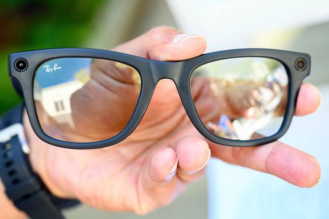 Meta Ray-Bans smart glasses. Hand holding black frames with dark tinted lenses in them.