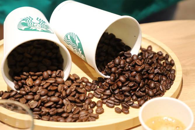 two paper Starbucks cups full of coffee beans, tipped on their sides