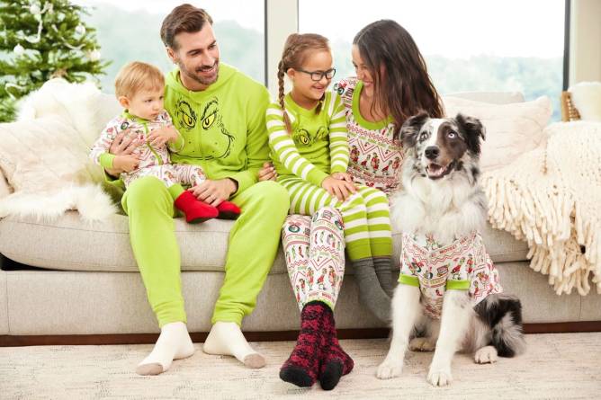 A family and their dog wear matching Grinch pajamas. 