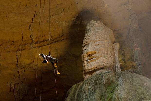 A tourist descends into Tianyan karst cave in China to explore a monumental Buddha statue.